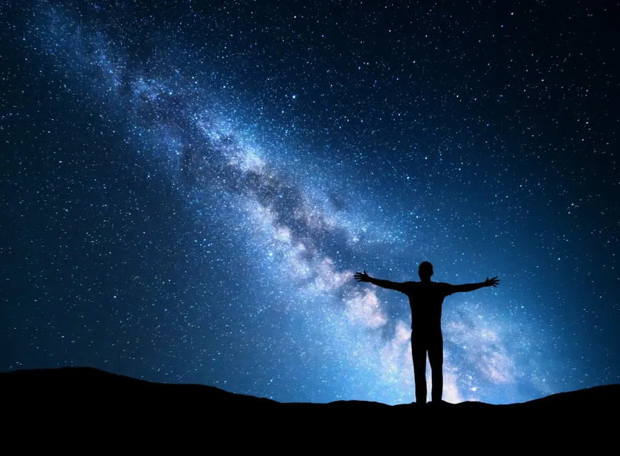 Silhouette with outstretched arms against the night sky
