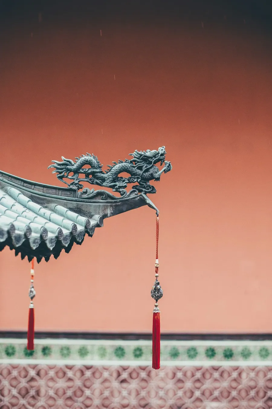 Close-up of a traditional Chinese dragon ornament on a roof with hanging tassels